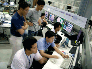 図1.　コンピュータで試験加速器を操作する研究者たち。