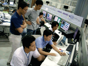 図1. コンピュータで試験加速器を操作する研究者たち。